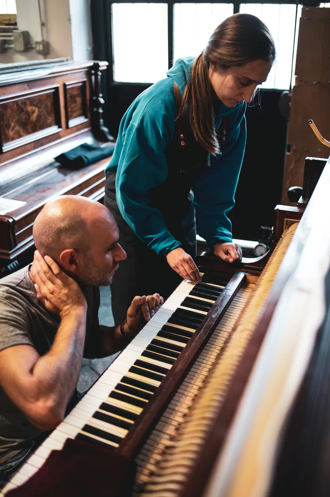 Al lavoro sulla meccanica di un pianoforte verticale, nel laboratorio della bottega
