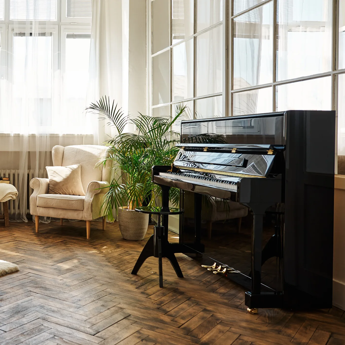 Pianoforte verticale nero lucido in un soggiorno con parquet a spina di pesce